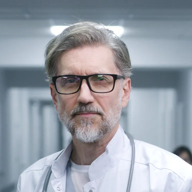 Photographie portrait d'un médecin âgé, lunettes, barbe grise, blouse blanche et stéthoscope
